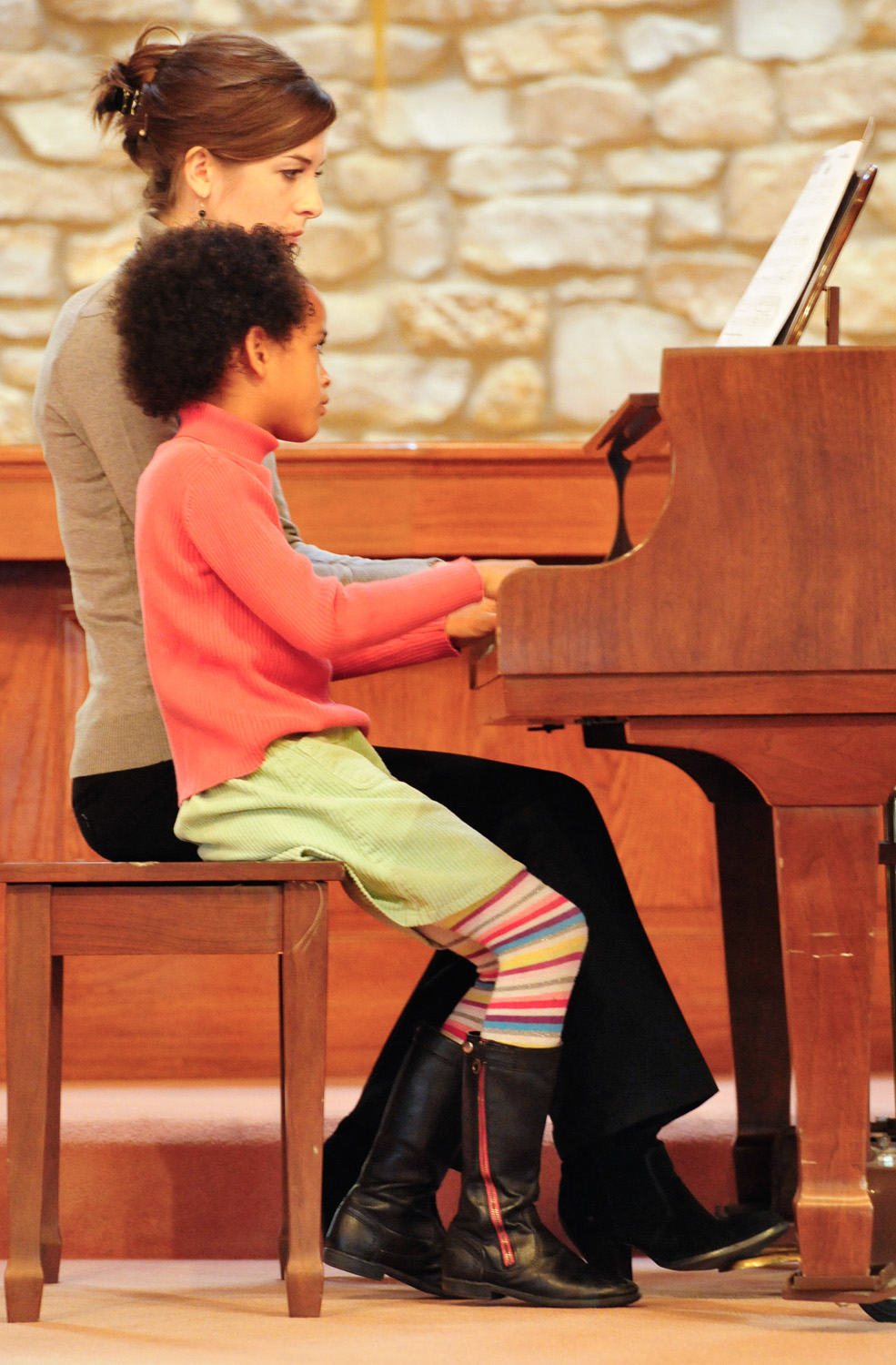 A young student playing piano with her teacher at the first Cincinnati School of Music recital